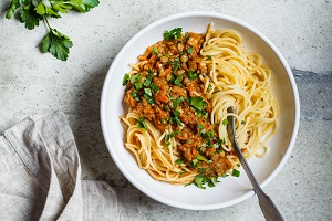 Ein Pastateller mit Spaghetti und Linsenbolognese, appetitlich mit Petersilie garniert, von oben drauf geschaut.